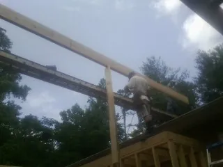 Carpenter setting a ridge beam over a new addition frame — Ice Dam Removal by Roofing Brothers in Cibolo