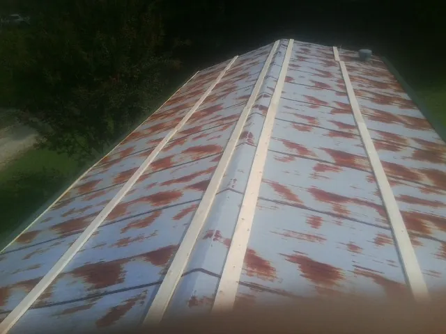 Rusted metal roof panels with new wood purlins before replacement in Cibolo