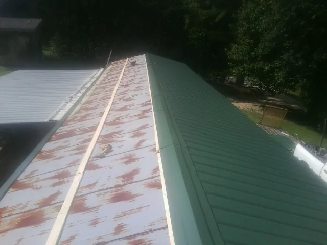 Old rusted panels beside newly installed green metal roofing — Wind Damage Roof Repair by Roofing Brothers in Cibolo