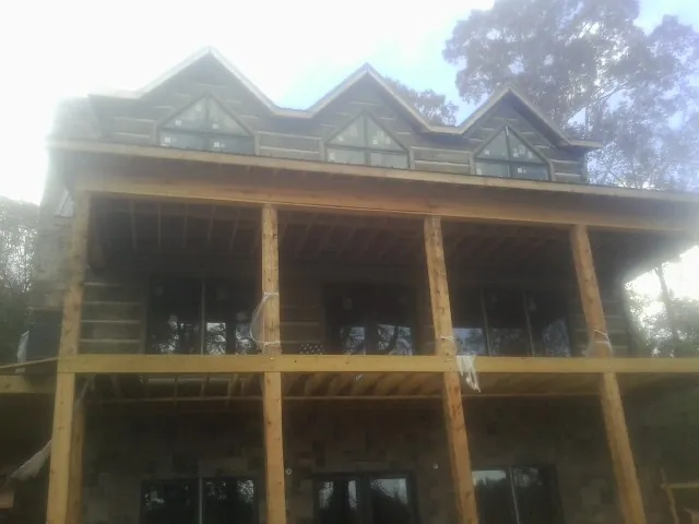Dormers and porch framing on a large log home under construction — Roof Coating work by our crew in Cibolo