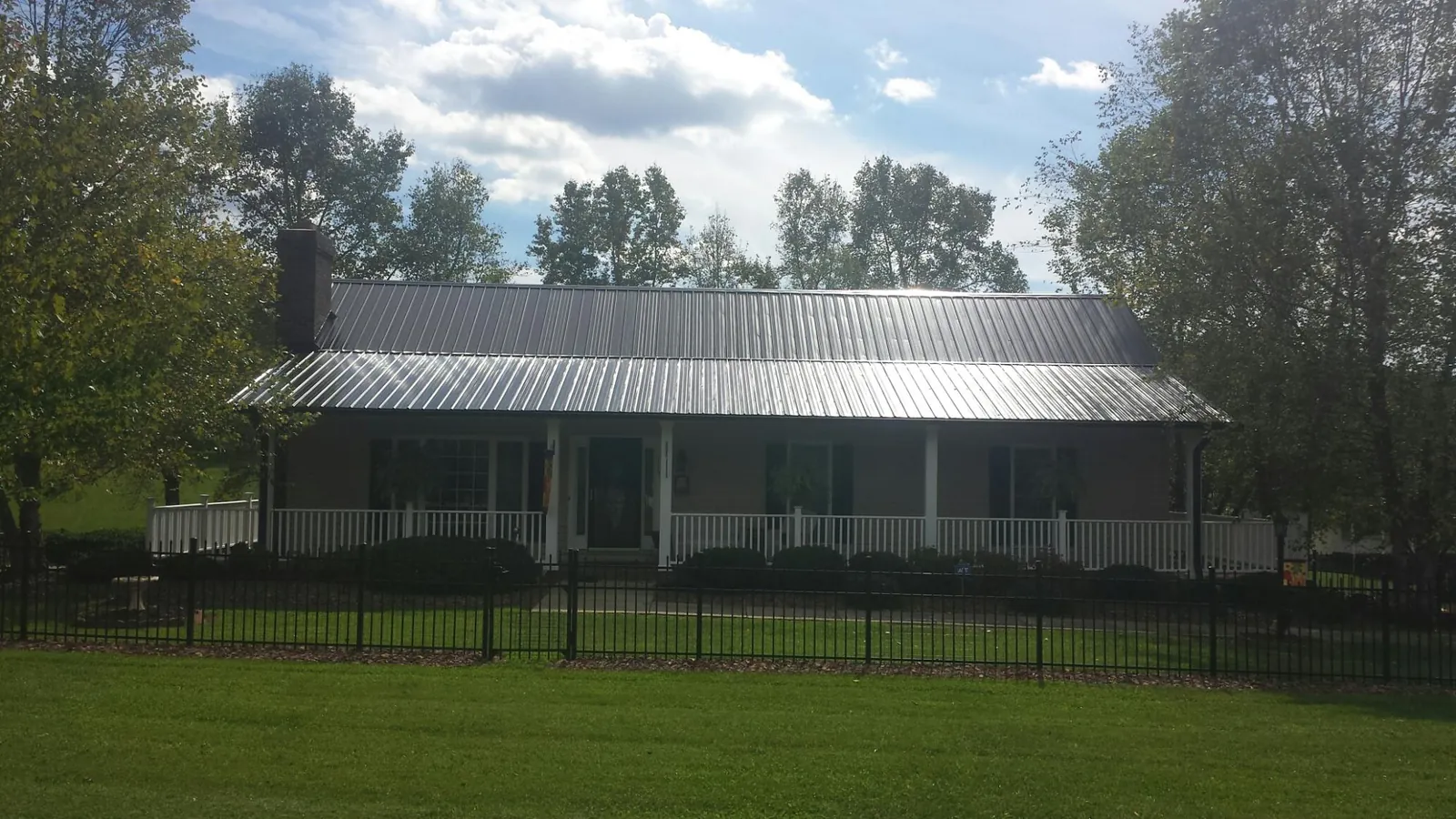 Gray metal roof on a brick ranch with a full width front porch — Gutter Guard Installation work by our crew in Cibolo