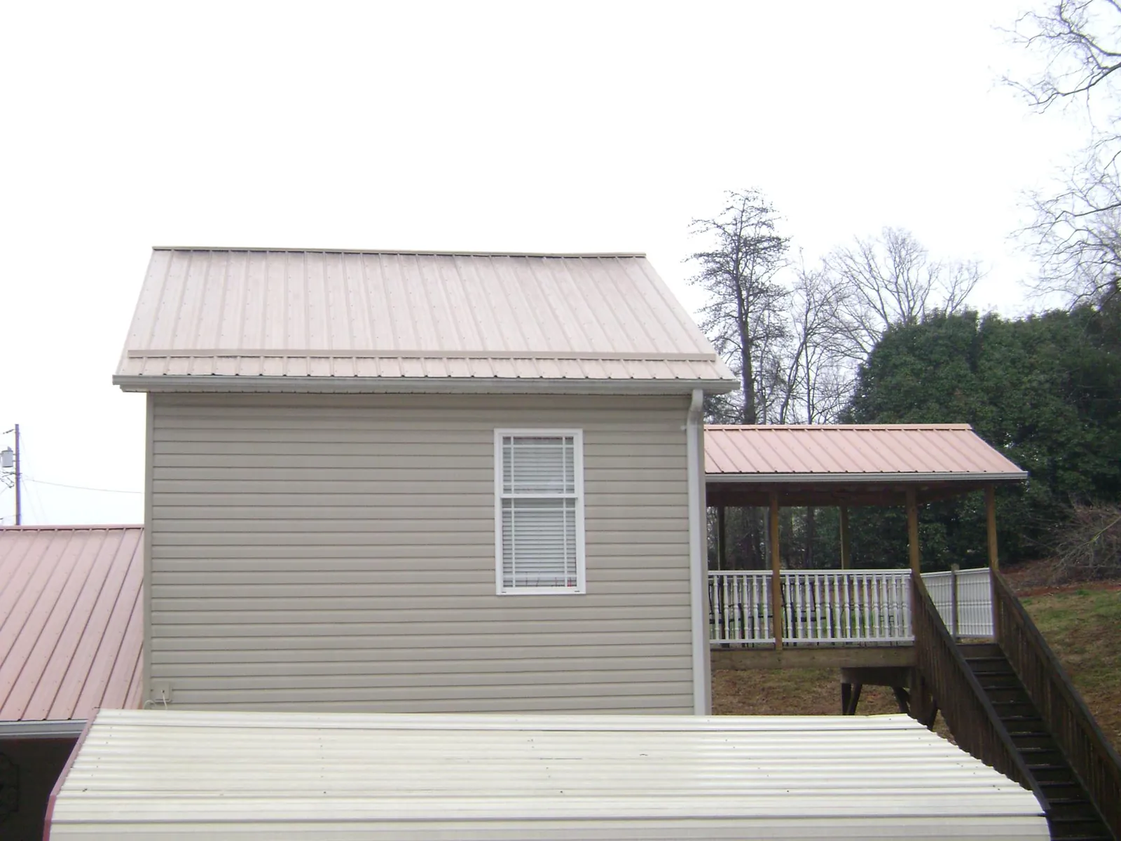 Tan metal roofs on a two story addition and attached porch, from a Roof Replacement job in Cibolo