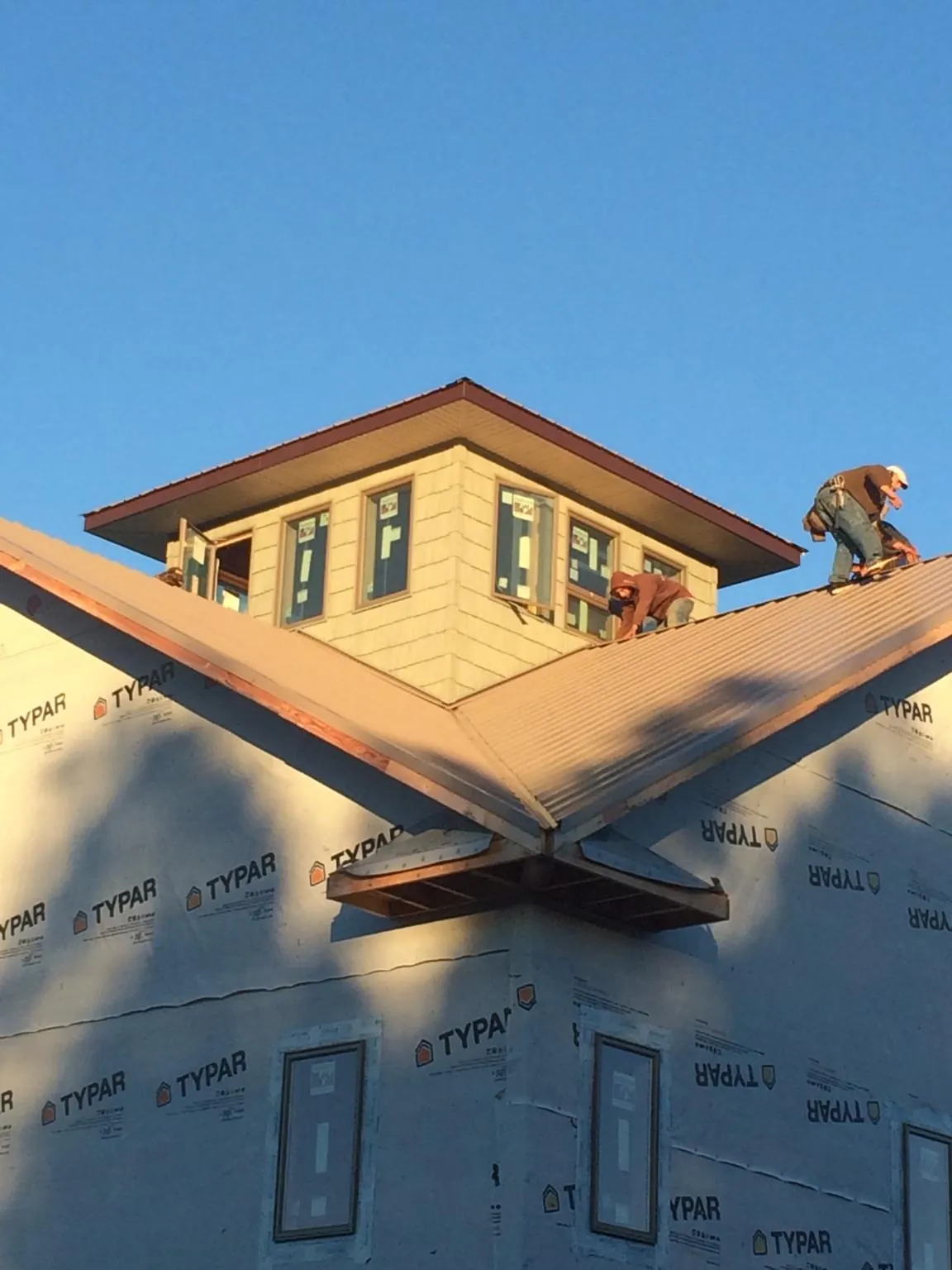 Roofers working around a rooftop cupola on a new metal roof at sunset — Roof Waterproofing in Cibolo by Roofing Brothers
